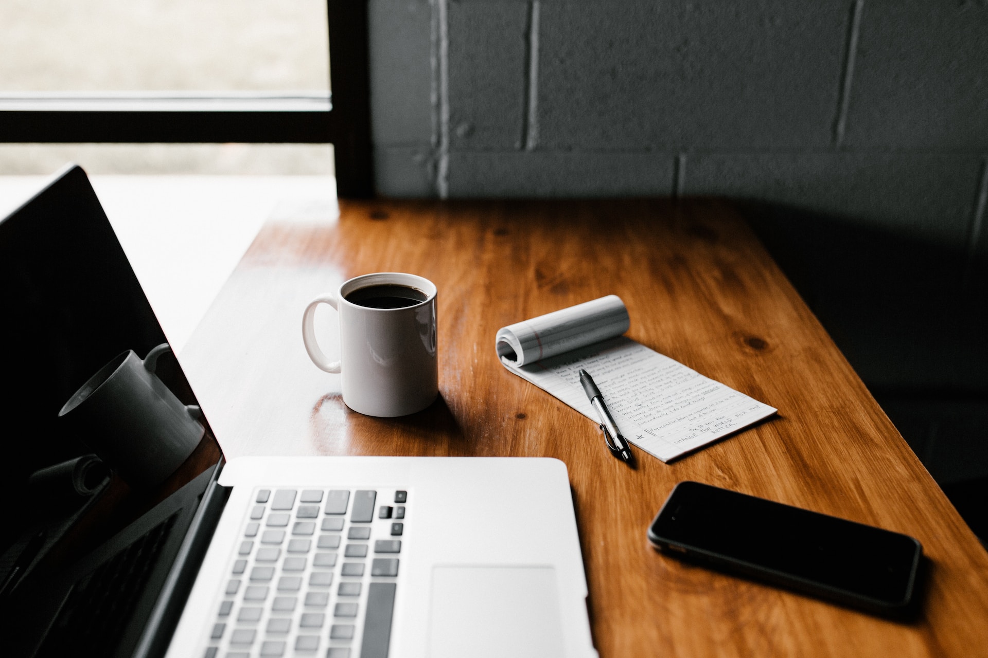 lifestyle image showing a laptop, notebook, pen and mobile phone